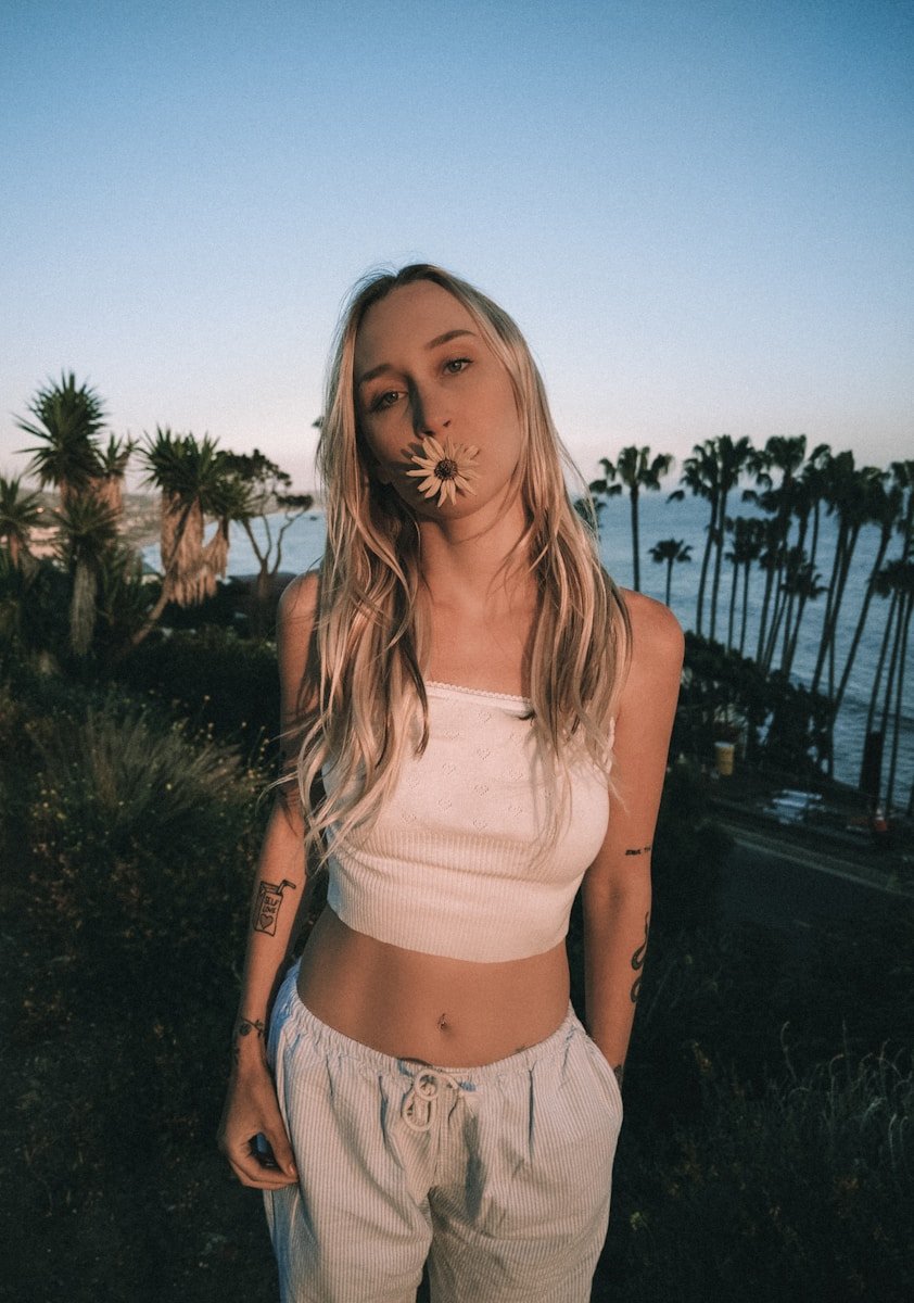 Woman with flower in mouth, palm trees, ocean view